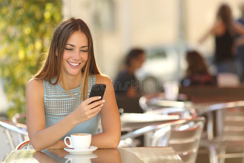 Muchacha que manda un SMS en el teléfono en un restaurante