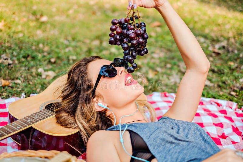 Muchacha que miente y que come las uvas en el parque imagenes de archivo Muchacha que miente y que come las uvas en el parque imagenes de archivo