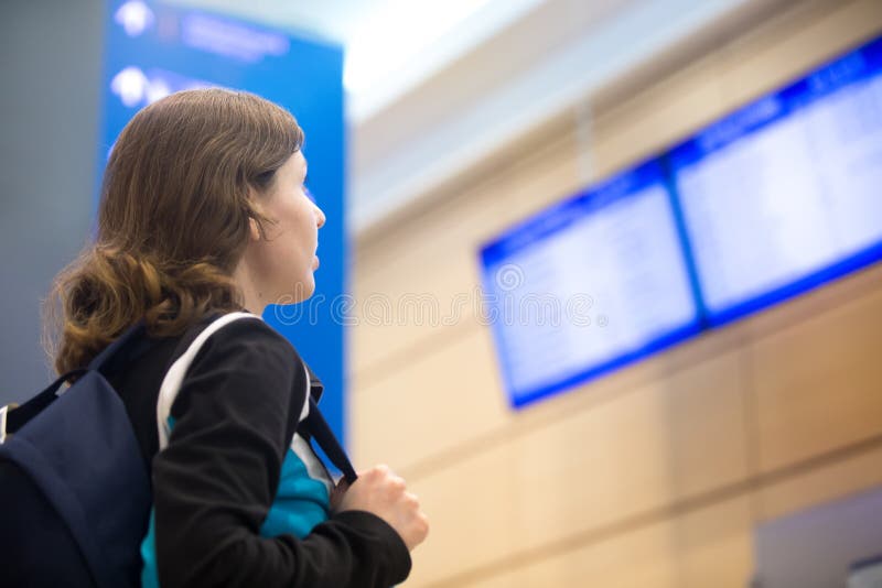 Muchacha que mira al tablero de la información del vuelo del aeropuerto imagen de archivo libre de regalías Muchacha que mira al tablero de la información del vuelo del aeropuerto imagen de archivo libre de regalías