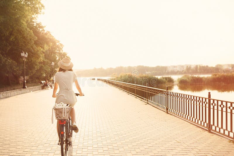 Muchacha que monta una bicicleta en parque cerca del lago fotos de archivo libres de regalías Muchacha que monta una bicicleta en parque cerca del lago fotos de archivo libres de regalías