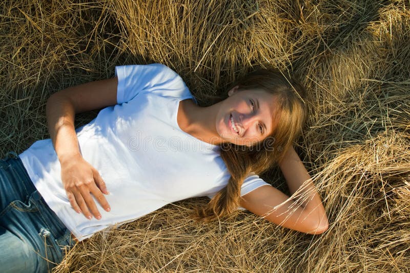 Muchacha que se reclina sobre la paja fresca fotografía de archivo libre de regalías Muchacha que se reclina sobre la paja fresca fotografía de archivo libre de regalías