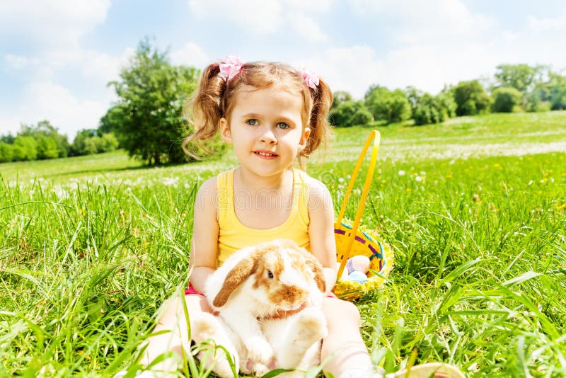 Muchacha que se sienta con el conejo lindo en el parque imágenes de archivo libres de regalías Muchacha que se sienta con el conejo lindo en el parque imágenes de archivo libres de regalías