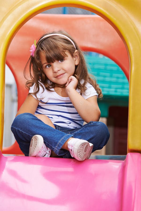 Muchacha que se sienta en asiento del sastre en diapositiva foto de archivo libre de regalías Muchacha que se sienta en asiento del sastre en diapositiva foto de archivo libre de regalías