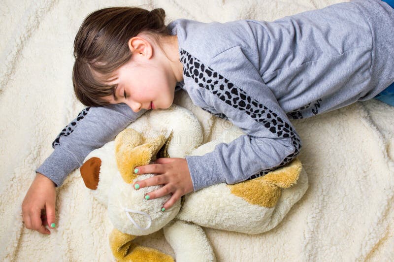 Muchacha que toma una siesta que abraza su juguete imágenes de archivo libres de regalías Muchacha que toma una siesta que abraza su juguete imágenes de archivo libres de regalías