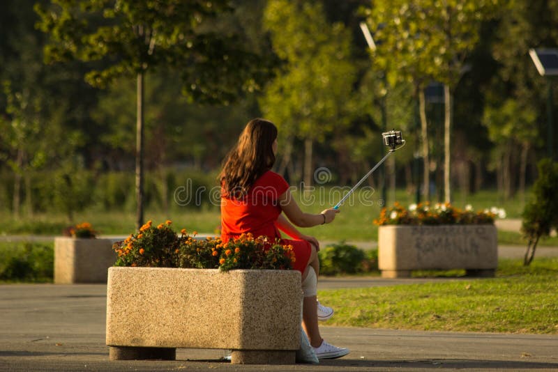 Muchacha que usa el palillo del selfie en parque Muchacha que usa el palillo del selfie en parque