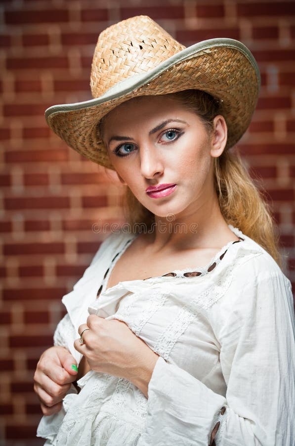 Muchacha rubia atractiva con el sombrero de paja y la blusa blanca fotos de archivo Muchacha rubia atractiva con el sombrero de paja y la blusa blanca fotos de archivo