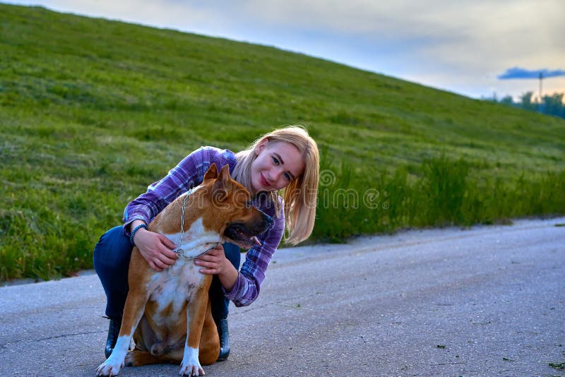 Muchacha rubia en un paseo de la tarde con un perro imagen de archivo libre de regalías