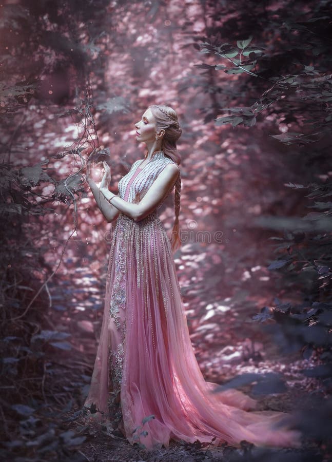 Muchacha rubia en un vestido rosado lujoso La bruja lleva a cabo magia en sus manos Peinado de Elven, trenza creativa imágenes de archivo libres de regalías Muchacha rubia en un vestido rosado lujoso La bruja lleva a cabo magia en sus manos Peinado de Elven, trenza creativa imágenes de archivo libres de regalías