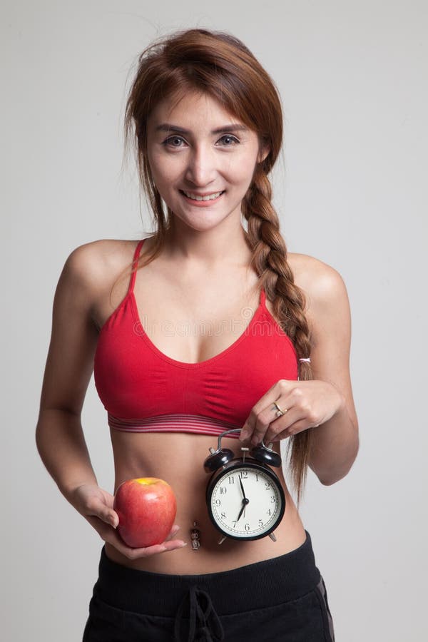 Muchacha sana asiática hermosa con el reloj y la manzana fotos de archivo Muchacha sana asiática hermosa con el reloj y la manzana fotos de archivo