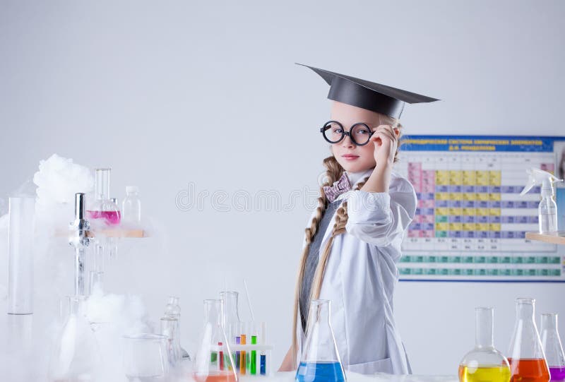 Muchacha seria que presenta al lado de la tabla para los experimentos imágenes de archivo libres de regalías
