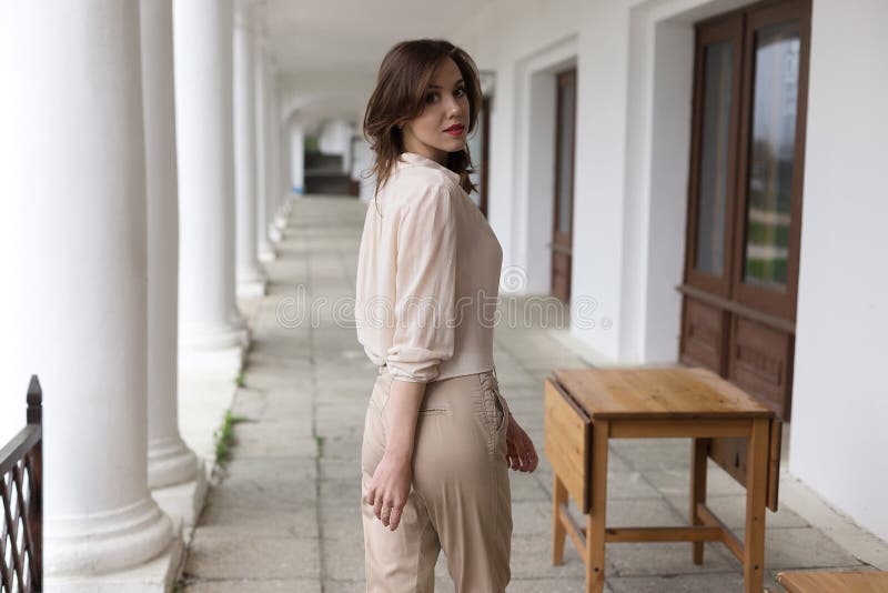 Muchacha sonriente caucásica joven hermosa con la situación roja atractiva de la barra de labios en el mirador con los pillarss b imágenes de archivo libres de regalías Muchacha sonriente caucásica joven hermosa con la situación roja atractiva de la barra de labios en el mirador con los pillarss b imágenes de archivo libres de regalías