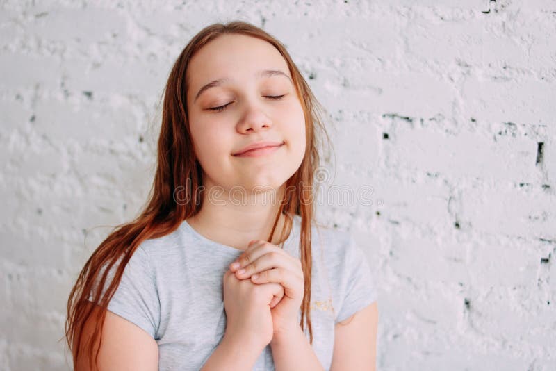 Muchacha sonriente del adolescente del pelirrojo encantador hermoso que se cierra los ojos y que hace un deseo aislado en la pare fotos de archivo libres de regalías Muchacha sonriente del adolescente del pelirrojo encantador hermoso que se cierra los ojos y que hace un deseo aislado en la pare fotos de archivo libres de regalías