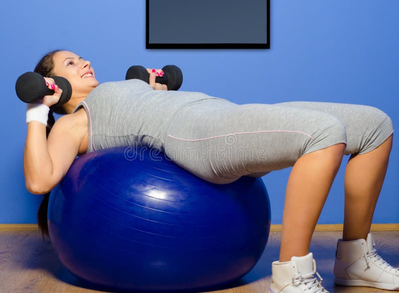 Muchacha sonriente que ejercita con pesas de gimnasia foto de archivo Muchacha sonriente que ejercita con pesas de gimnasia foto de archivo