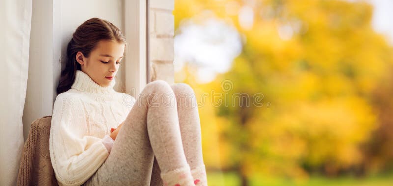 Muchacha triste que se sienta en ventana del travesaño en casa en otoño imagen de archivo Muchacha triste que se sienta en ventana del travesaño en casa en otoño imagen de archivo