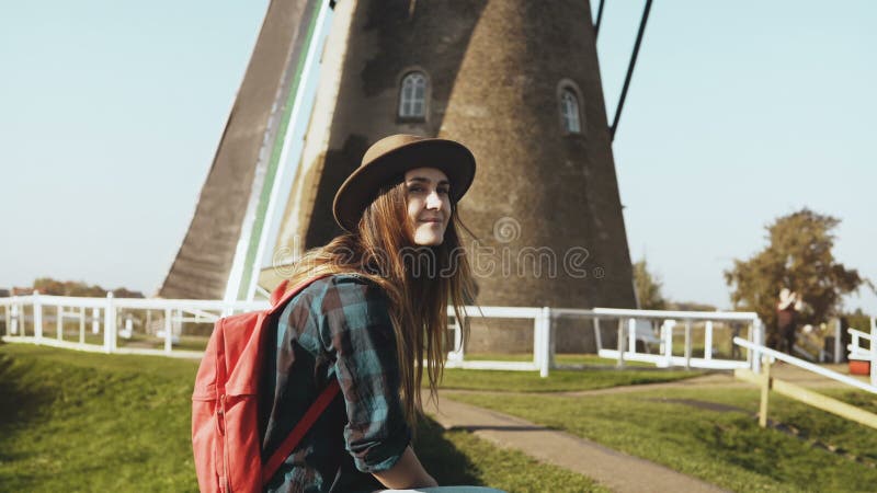 Muchacha turística bastante europea cerca del molino de viento viejo La mujer joven hermosa en sombrero con el pelo largo se sien