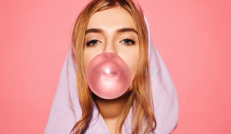 Muchacha vestida en sudadera con capucha azul y burbuja que sopla con el chicle foto de archivo libre de regalías Muchacha vestida en sudadera con capucha azul y burbuja que sopla con el chicle foto de archivo libre de regalías