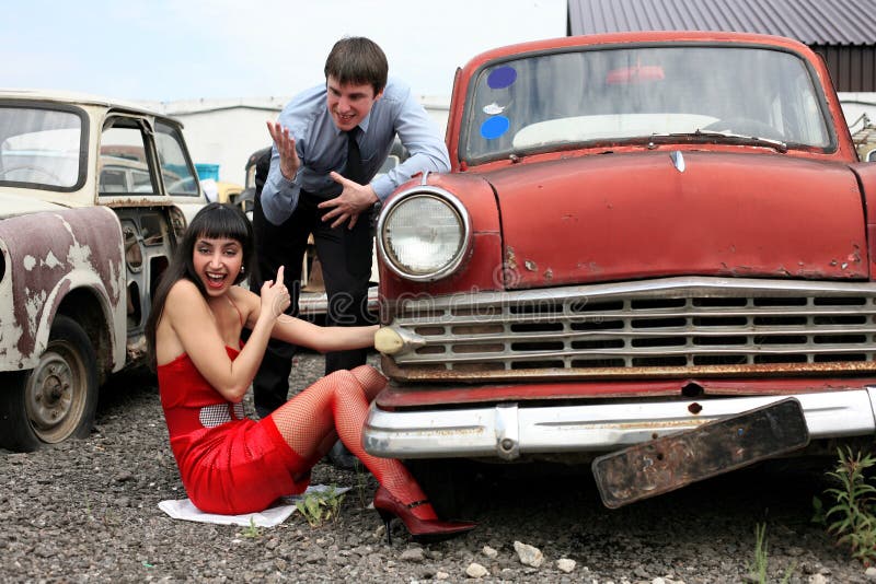 Couple at retro car- under constructions to wheel. Couple at retro car- under constructions to wheel