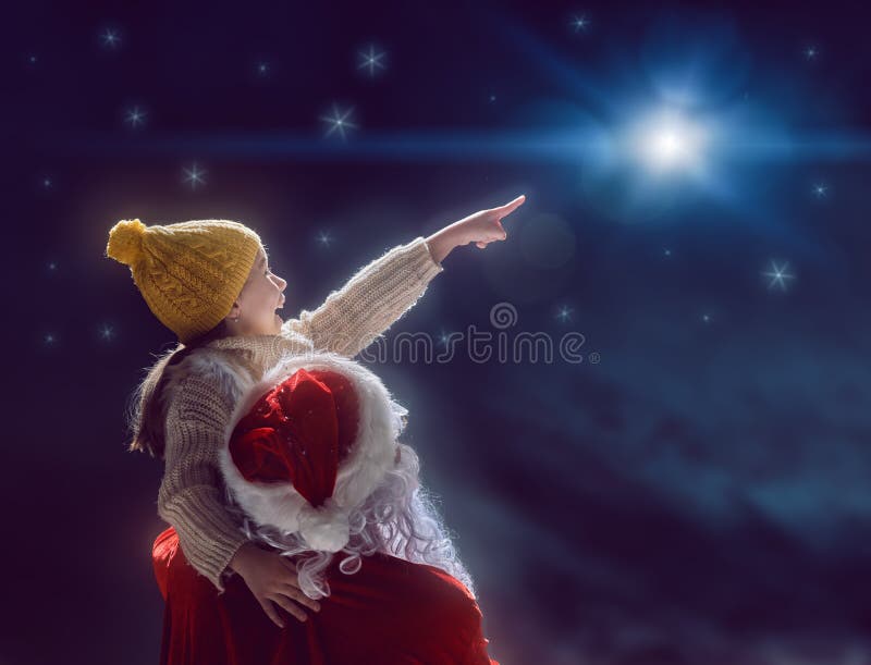 Muchacha y Santa Claus que miran la estrella de la Navidad imagen de archivo libre de regalías