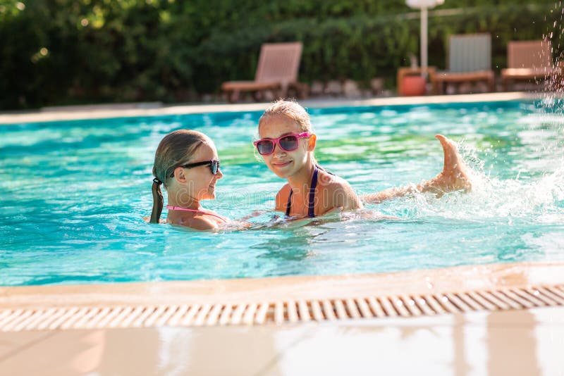 Muchachas hermosas felices que se divierten en la piscina imagen de archivo libre de regalías Muchachas hermosas felices que se divierten en la piscina imagen de archivo libre de regalías