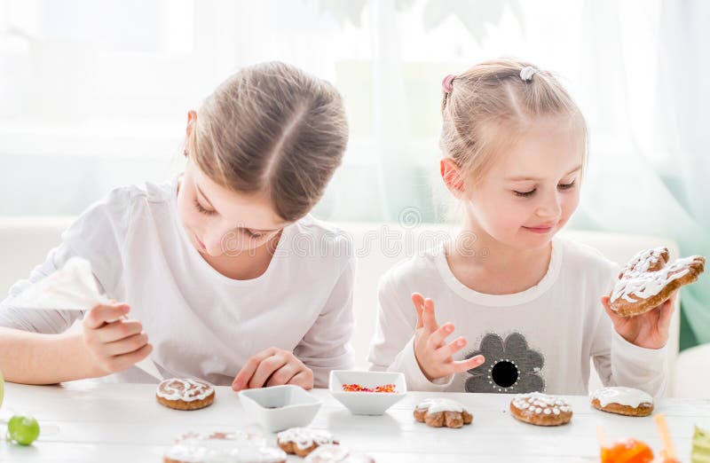 Muchachas lindas que adornan las galletas de Pascua imágenes de archivo libres de regalías Muchachas lindas que adornan las galletas de Pascua imágenes de archivo libres de regalías