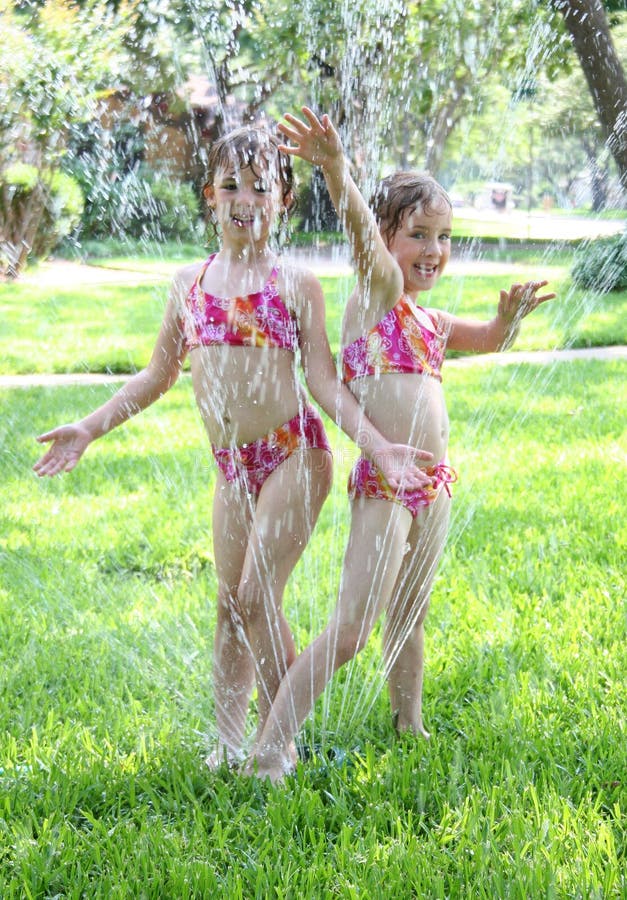 Muchachas que juegan en regadera imágenes de archivo libres de regalías Muchachas que juegan en regadera imágenes de archivo libres de regalías