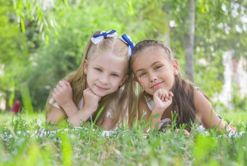 Muchachas sonrientes que mienten en hierba verde en el parque en verano foto de archivo libre de regalías Muchachas sonrientes que mienten en hierba verde en el parque en verano foto de archivo libre de regalías