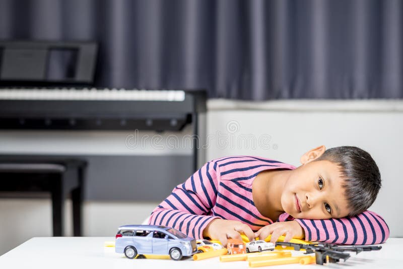 Muchacho asiático joven que juega el juguete del coche en el cuarto imagen de archivo Muchacho asiático joven que juega el juguete del coche en el cuarto imagen de archivo