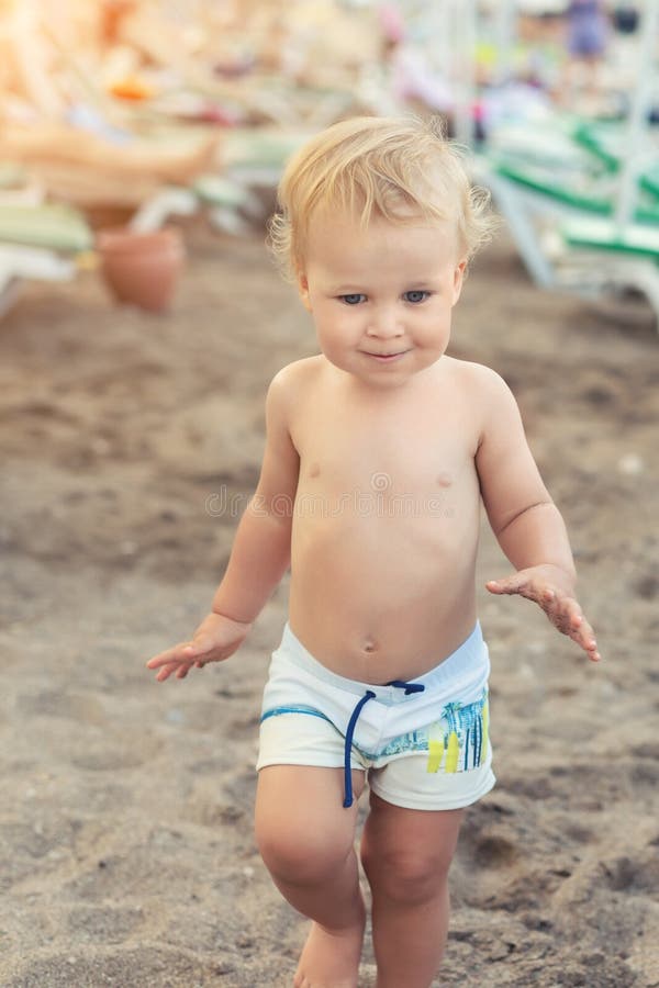 Muchacho caucásico lindo del toodler que camina solamente en la playa arenosa entre el calesa-salón Niño feliz adorable que se di fotografía de archivo Muchacho caucásico lindo del toodler que camina solamente en la playa arenosa entre el calesa-salón Niño feliz adorable que se di fotografía de archivo