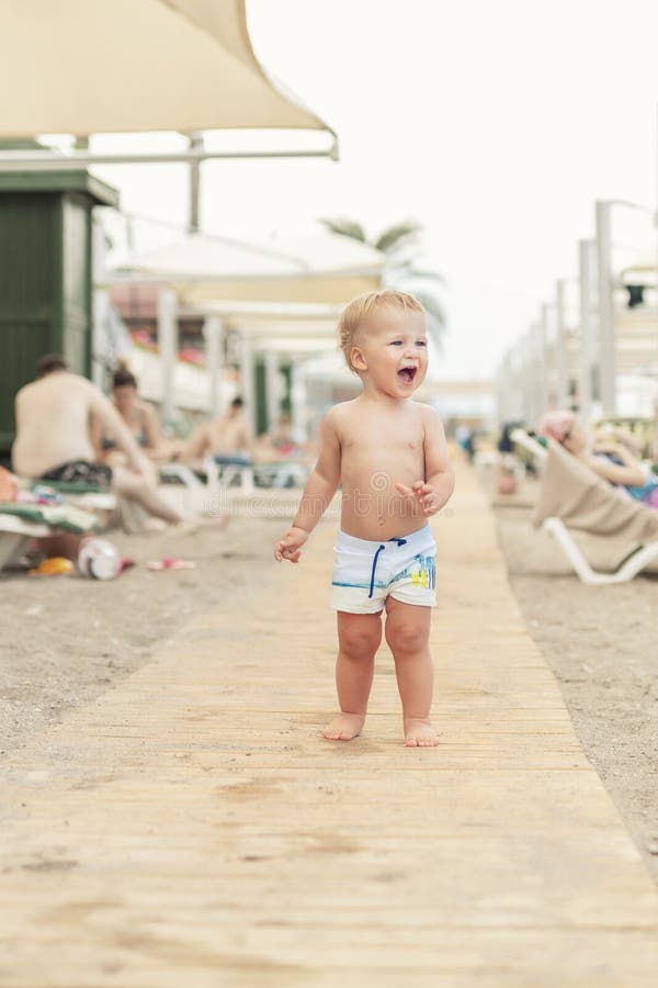 Muchacho caucásico lindo del toodler que camina solamente en la playa arenosa entre el calesa-salón Niño feliz adorable que se di fotografía de archivo Muchacho caucásico lindo del toodler que camina solamente en la playa arenosa entre el calesa-salón Niño feliz adorable que se di fotografía de archivo