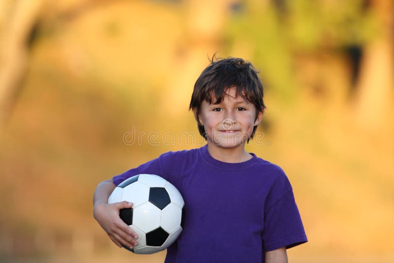 Muchacho con el balón de fútbol en la puesta del sol fotografía de archivo libre de regalías Muchacho con el balón de fútbol en la puesta del sol fotografía de archivo libre de regalías
