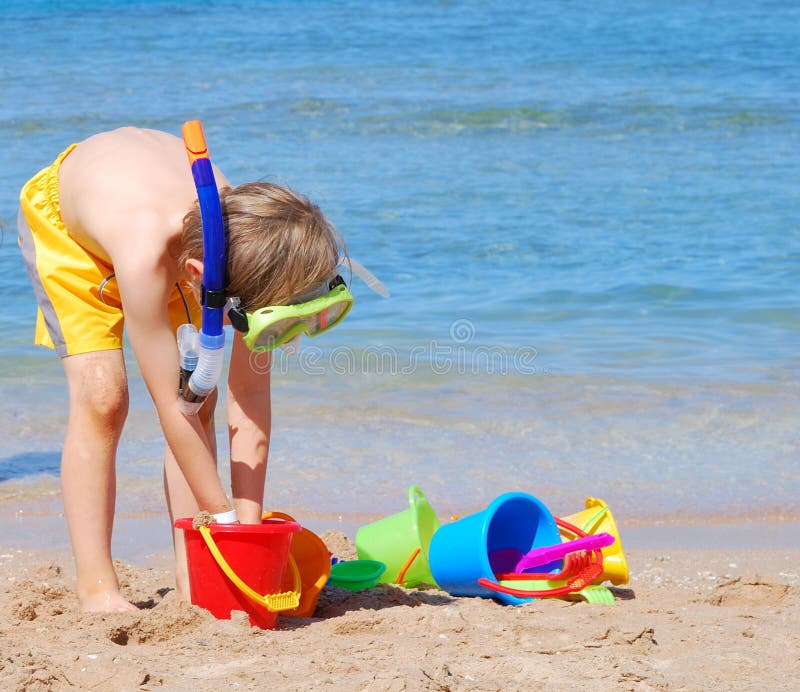 Boy with snorkeling equipment and plastic buckets on the beach. Boy with snorkeling equipment and plastic buckets on the beach.