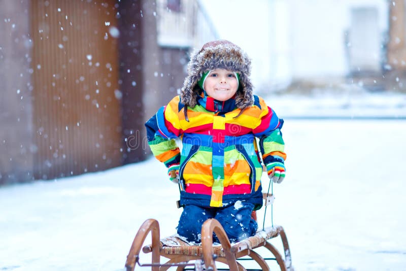 Muchacho del ni?o que disfruta de paseo del trineo durante las nevadas Montar a caballo preescolar feliz del ni?o en el trineo de foto de archivo Muchacho del ni?o que disfruta de paseo del trineo durante las nevadas Montar a caballo preescolar feliz del ni?o en el trineo de foto de archivo