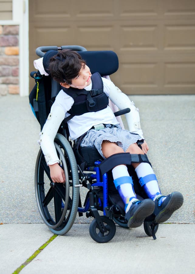 Muchacho discapacitado biracial de siete años en silla de ruedas