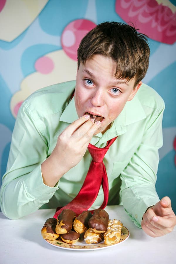 Muchacho divertido que come al hombre dulce de las tortas, hambriento y de caramelo imagen de archivo libre de regalías Muchacho divertido que come al hombre dulce de las tortas, hambriento y de caramelo imagen de archivo libre de regalías