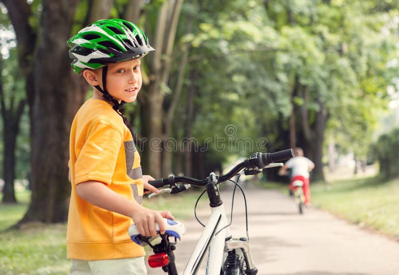 Muchacho en casco seguro con la bicicleta en parque de la ciudad imagen de archivo Muchacho en casco seguro con la bicicleta en parque de la ciudad imagen de archivo