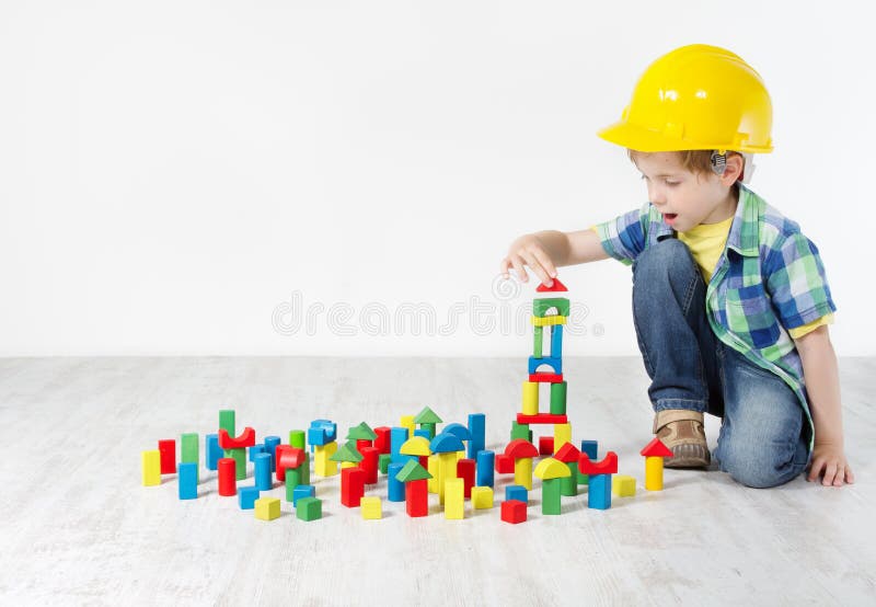 Muchacho en el sombrero duro que juega con los bloques fotografía de archivo