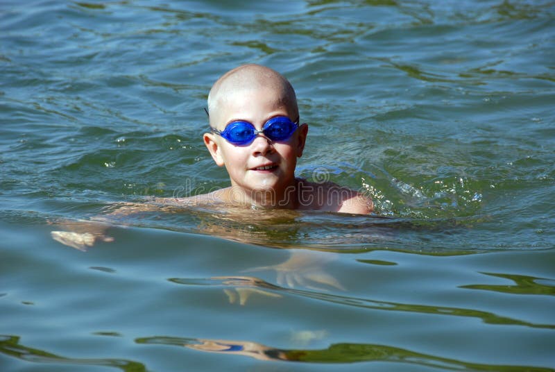 Happy young boy in googles is swimming in the lake. Happy young boy in googles is swimming in the lake