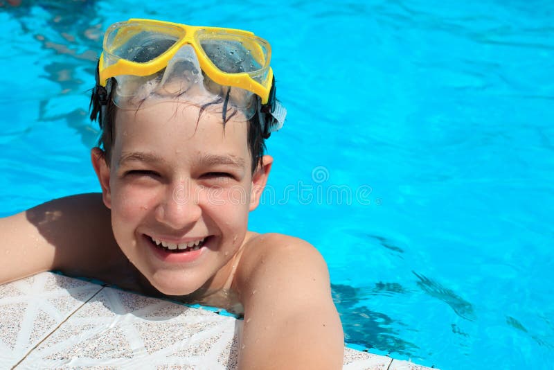 Happy, smiling boy with goggles in water at the edge of a swimming pool. Happy, smiling boy with goggles in water at the edge of a swimming pool.