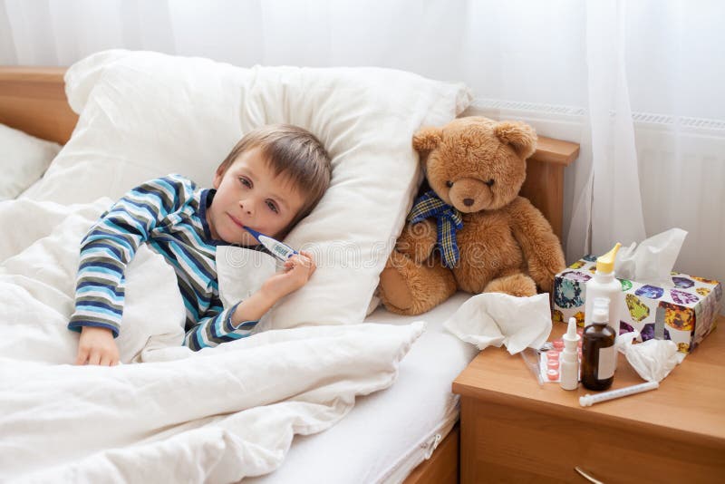 Muchacho enfermo del niño que miente en cama con una fiebre, descansando imagen de archivo Muchacho enfermo del niño que miente en cama con una fiebre, descansando imagen de archivo