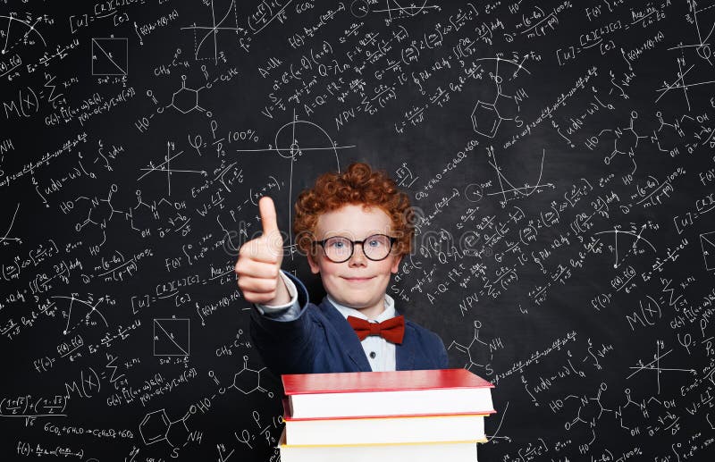 Muchacho hermoso sonriente del niño en mano de la tenencia del traje con el pulgar para arriba contra la pizarra De nuevo a conce imágenes de archivo libres de regalías Muchacho hermoso sonriente del niño en mano de la tenencia del traje con el pulgar para arriba contra la pizarra De nuevo a conce imágenes de archivo libres de regalías