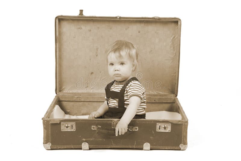 Muchacho joven que se sienta en una maleta imagen de archivo Muchacho joven que se sienta en una maleta imagen de archivo