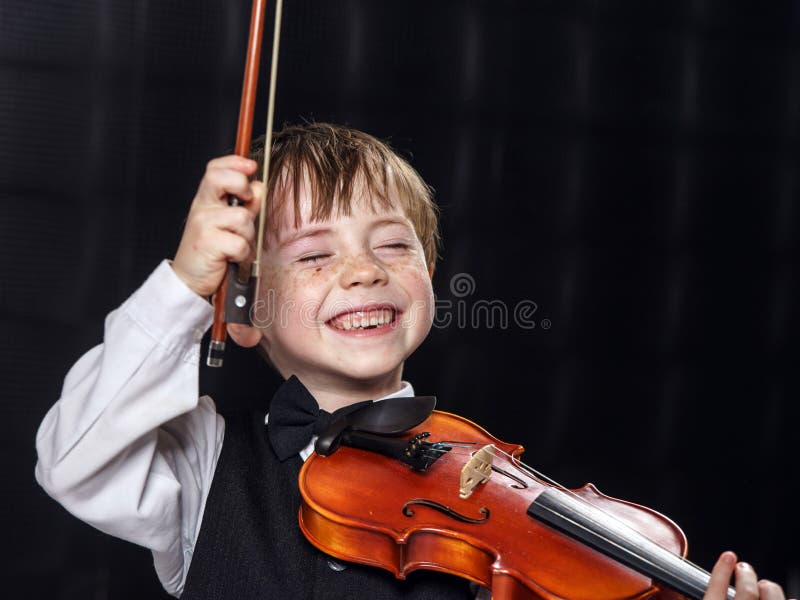 Muchacho pecoso del rojo-pelo que toca el violín. imagen de archivo libre de regalías Muchacho pecoso del rojo-pelo que toca el violín. imagen de archivo libre de regalías