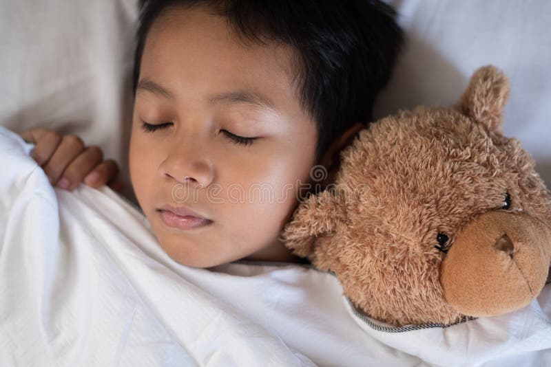 Boy sleeping on bed with teddy bear white pillow and sheets.boy fall asleep in morning.sleep concept. Boy sleeping on bed with teddy bear white pillow and sheets.boy fall asleep in morning.sleep concept