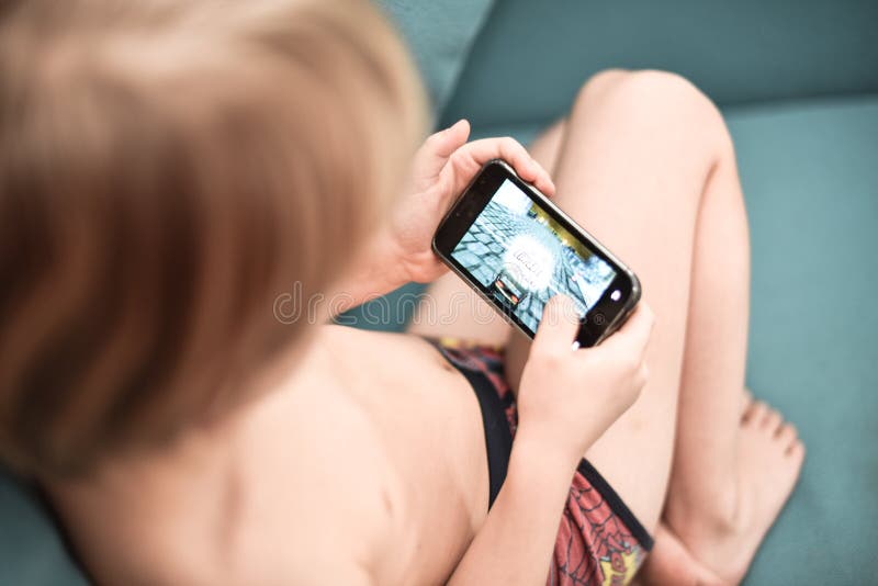 Muchacho que juega al videojuego en un teléfono móvil imagenes de archivo Muchacho que juega al videojuego en un teléfono móvil imagenes de archivo