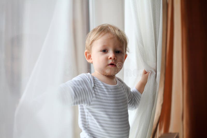 Muchacho que juega con las cortinas imagen de archivo Muchacho que juega con las cortinas imagen de archivo