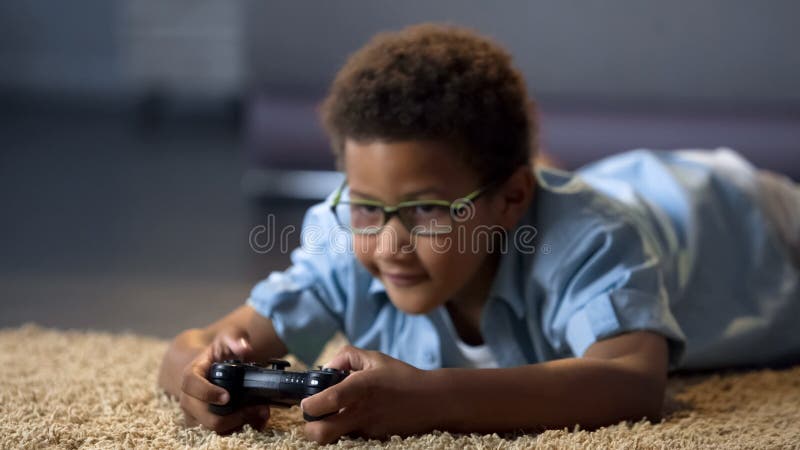 Muchacho que mira la pantalla mientras que juega al videojuego, daño de la salud, forma de vida sedentaria foto de archivo libre de regalías