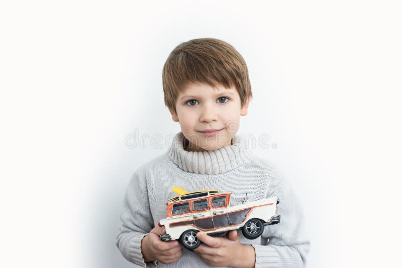 Muchacho que sostiene un coche retro del juguete en un fondo blanco imágenes de archivo libres de regalías Muchacho que sostiene un coche retro del juguete en un fondo blanco imágenes de archivo libres de regalías