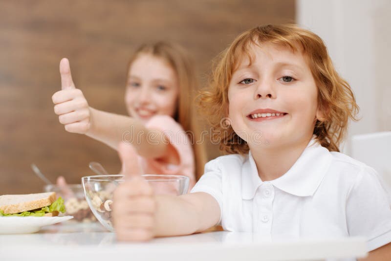 Muchacho sonriente adorable que goza del desayuno con su hermana imágenes de archivo libres de regalías Muchacho sonriente adorable que goza del desayuno con su hermana imágenes de archivo libres de regalías