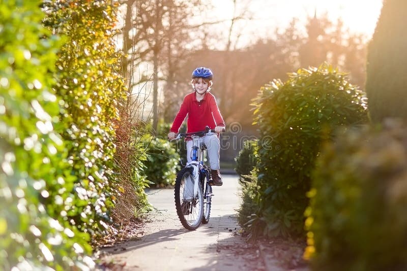 Muchacho sonriente feliz del adolescente que monta su bici en puesta del sol imagenes de archivo Muchacho sonriente feliz del adolescente que monta su bici en puesta del sol imagenes de archivo