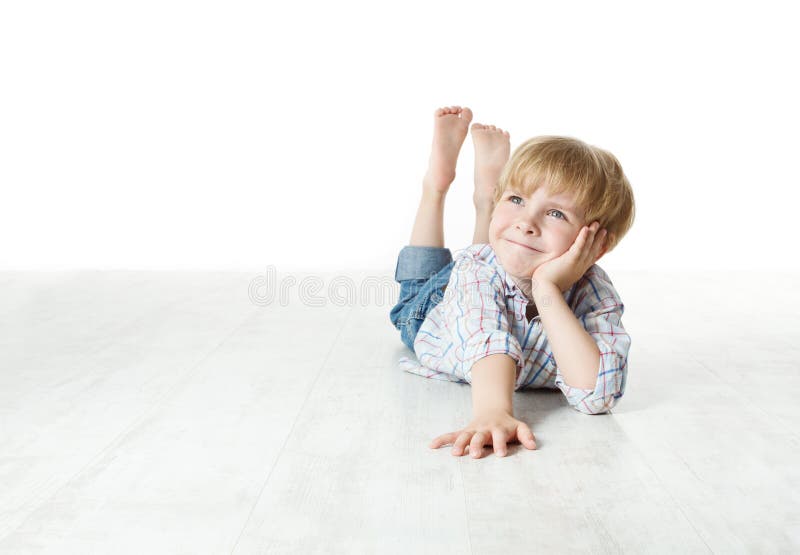 Thinking smiling little boy lying down on floor and looking up to the side. Thinking smiling little boy lying down on floor and looking up to the side